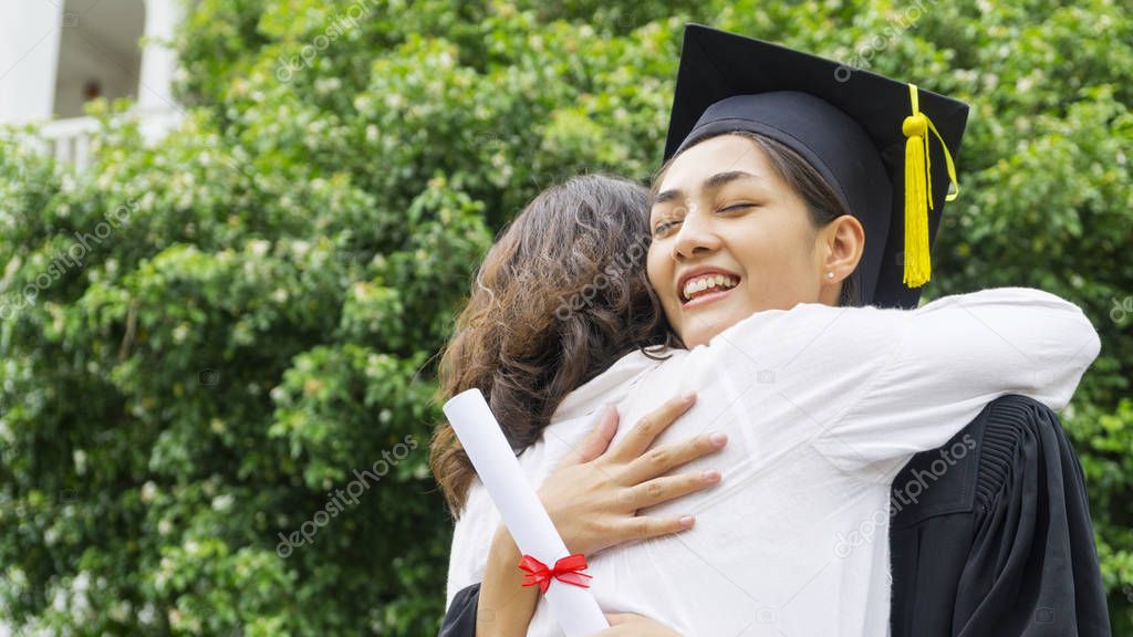 girl student with the Graduation gowns and hat hug the parent in congratulation ceremony.