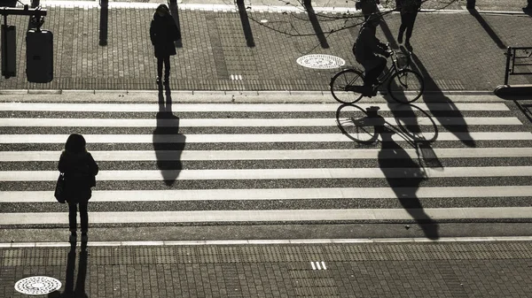 Personas silueta caminar en el paso peatonal en la calle de cruce de la ciudad de negocios al atardecer con la sombra oscura de la gente en la carretera (vista aérea superior ) —  Fotos de Stock