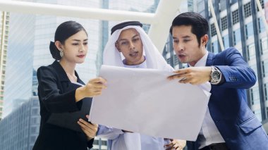 Asyalı iş adamları. Zeki erkekler ve kadınlar konuşur ve projeyi yayalar üzerinde sunarlar. Şehir meydanında modern bina boyunca yürürler.