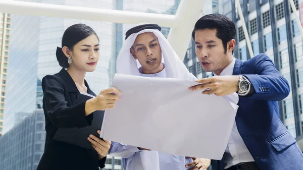 Asyalı iş adamları. Zeki erkekler ve kadınlar konuşur ve projeyi yayalar üzerinde sunarlar. Şehir meydanında modern bina boyunca yürürler.