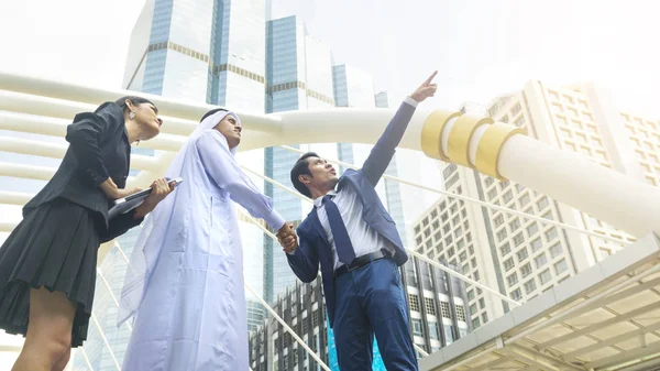 Equipe asiático negócios pessoas inteligente homem e mulher falar e apertar a mão o árabe homem no exterior cidade edifício — Fotografia de Stock