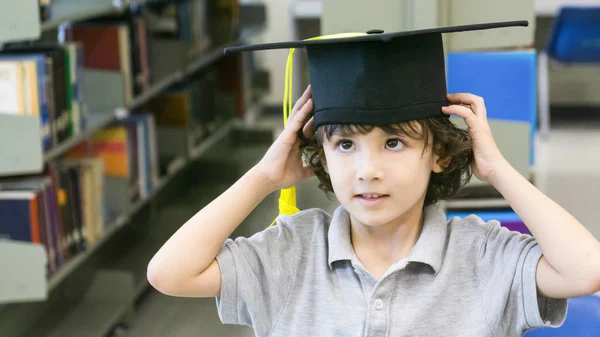 Sonriente chico blanco con el casquillo de graduación y soporte de papel diploma — Foto de Stock