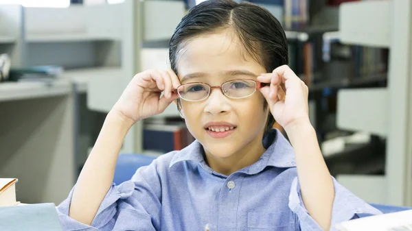 Sorridente engraçado bonito menino sentado e segure os óculos no rosto — Fotografia de Stock