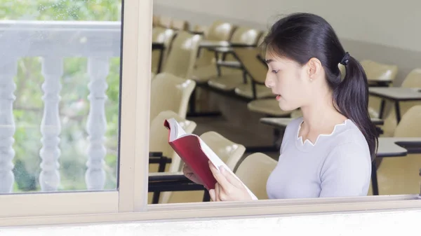 La ragazza asiatica legge un libro rosso — Foto Stock