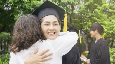 kız öğrenci mezuniyet önlük ve şapka ile sarılmak üst kutlama töreni.