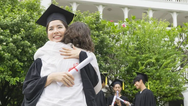 Fille étudiante avec les robes de remise des diplômes et chapeau étreindre le parent dans la cérémonie de félicitations . — Photo