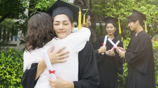 girl student with the Graduation gowns and hat hug the parent in