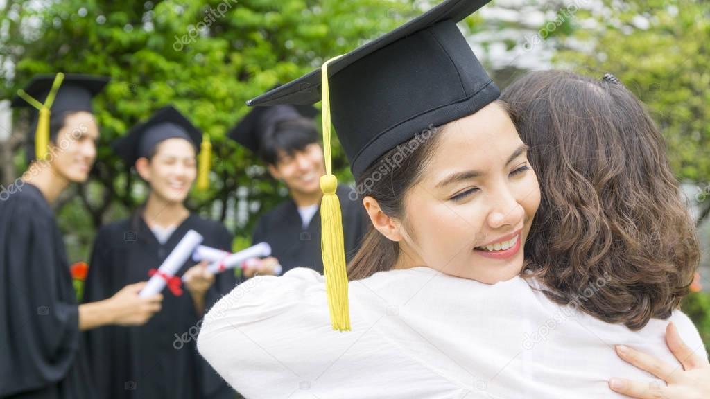 girl student with the Graduation gowns and hat hug the parent in congratulation ceremony.