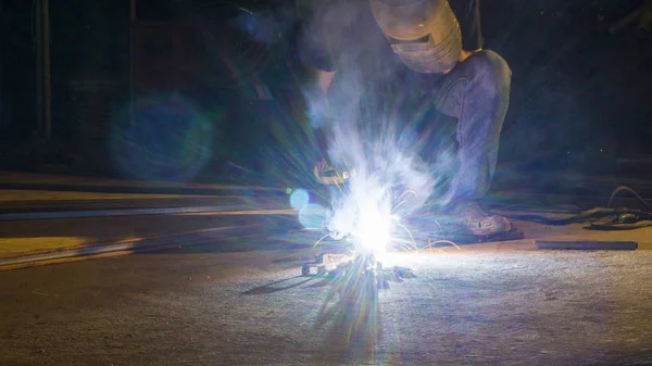 Dělník, svařování kovů, zaměření na flash světelné linie ostrých jiskru, při slabém osvětlení — Stock fotografie