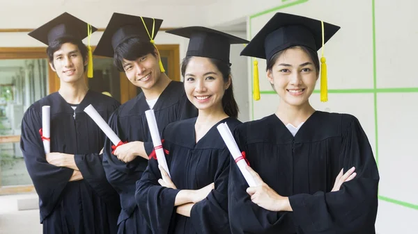 Las personas estudiantes hombre y mujer con vestidos de graduación negro mantener el diploma y estar juntos. Con la sensación de felicidad y elegancia . —  Fotos de Stock