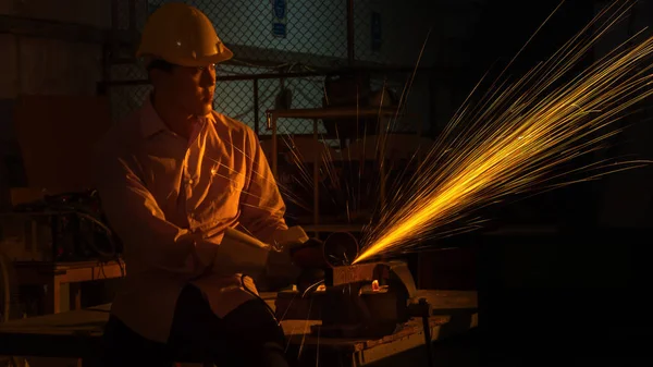 O trabalhador homem usa máquina de corte de moagem para cortar metal, foco na linha de luz de flash de faísca afiada, em baixa luz — Fotografia de Stock