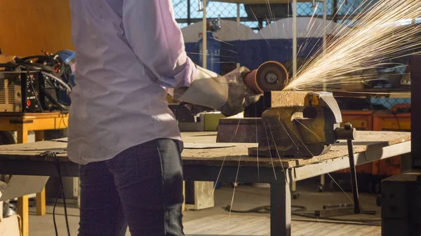 Εργάτης χρησιμοποιεί λείανση κομμένα μέταλλα, εστίαση σε φλας γραμμή φωτός από αιχμηρή σπίθα, σε χαμηλό φως — Φωτογραφία Αρχείου