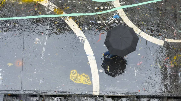 Haut du parapluie noir et personne marche sur sol noir humide avec r — Photo