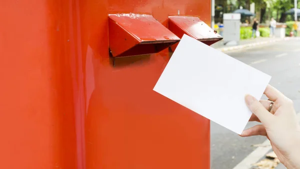 Ręka z pocztówki i spadek postbox czerwony poczty — Zdjęcie stockowe