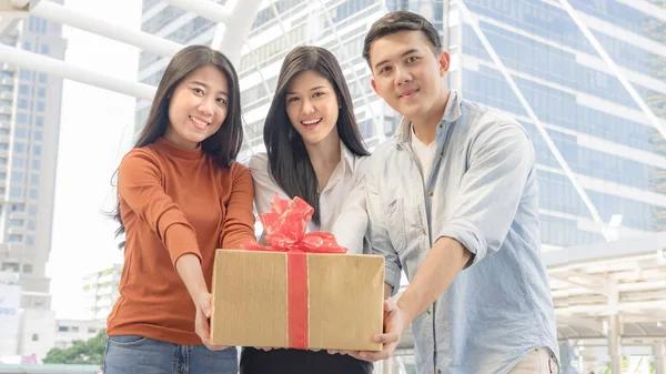 Persone tengono scatola di regalo con nastro rosso — Foto Stock