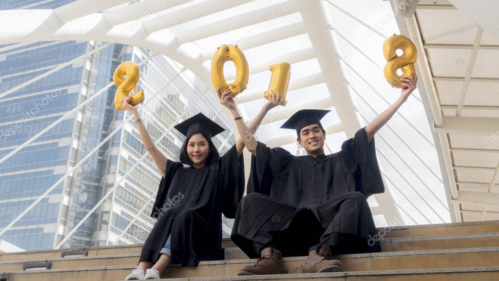 students in graduation suit sit and gold number balloons 2018