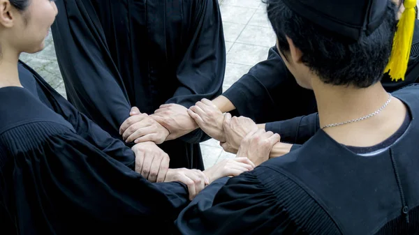 Les personnes avec des robes noires joignent la main dans la boucle circulaire — Photo