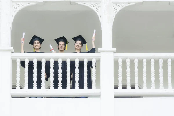 Studenti nel sentirsi felici con abiti di laurea stand a corrido — Foto Stock