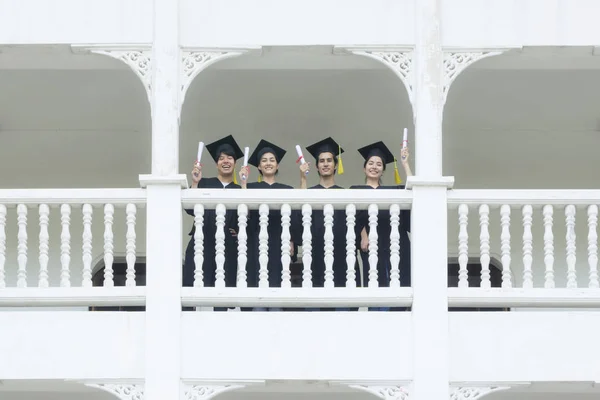 Studenti nel sentirsi felici con abiti di laurea stand a corrido — Foto Stock