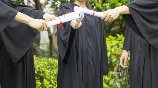 Pessoas com vestidos de graduação preto possuem diploma . — Fotografia de Stock