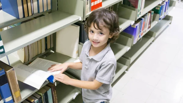 Sonriente Chico Blanco Con Libro Estantería Fondo — Foto de Stock