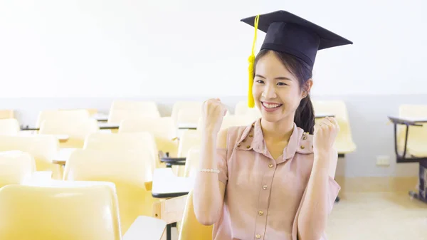 Menina estudante com o chapéu de formatura em sala de aula — Fotografia de Stock
