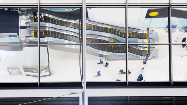 reflection glass of top view people walk and sit stair escalator at airport