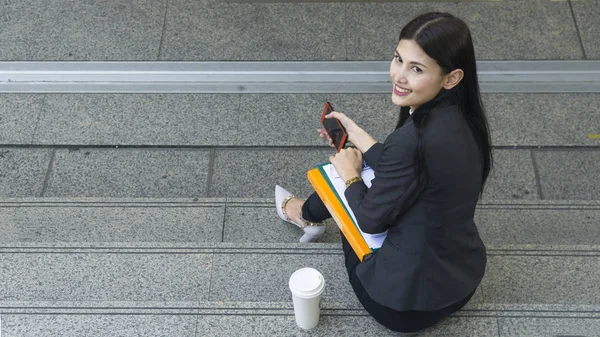 Portrait of business asian women in feeling of confident and happy uses smartphoone at outdoor pedestrian walk way