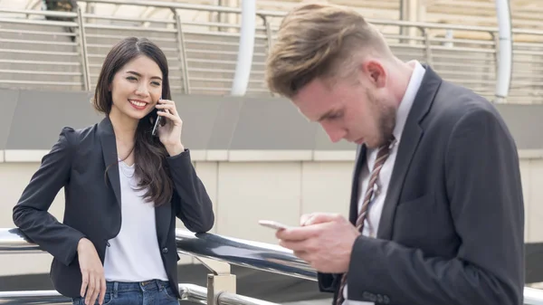 Grupo de pessoas empreendedoras usa telefone olhar inteligente móvel. Jovens empresários bonitos vestindo vestido terno estritamente elegante . — Fotografia de Stock