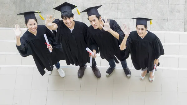 Le persone sono felici in abiti di laurea e cap stand in linea  ( — Foto Stock