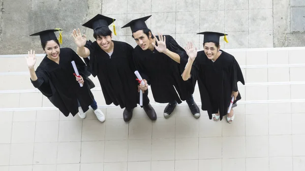 Le persone sono felici in abiti di laurea e cap stand in linea  ( — Foto Stock