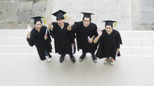 Le persone sono felici in abiti di laurea e cap stand in linea  ( — Foto Stock