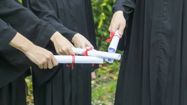 Pessoas com vestidos de graduação preto possuem diploma . — Fotografia de Stock