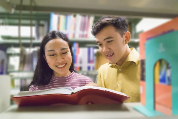 Homme et femme lire et parler livre ouvert à la bibliothèque — Photo