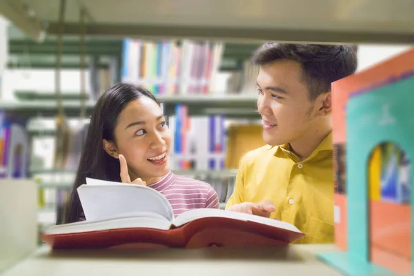 Mann und Frau lesen und reden Buch im Bücherregal auf — Stockfoto