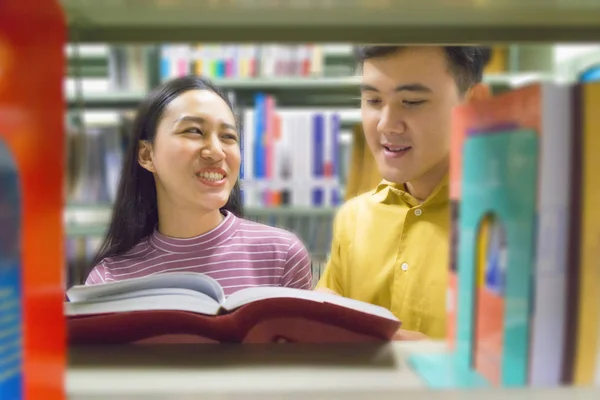 Homem e mulher ler e falar livro aberto na estante — Fotografia de Stock