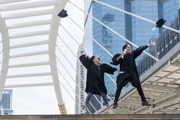 Felice laureato teen persone che saltano con gli abiti di laurea in — Foto Stock