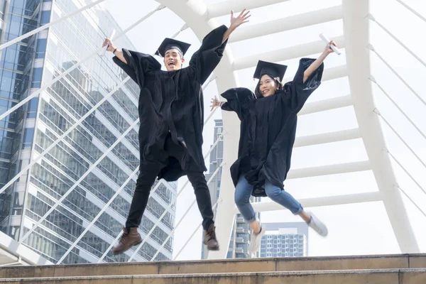 Felice laureato teen persone che saltano con gli abiti di laurea in — Foto Stock