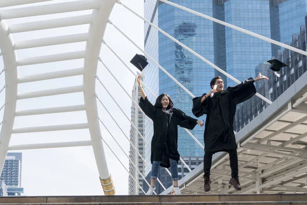 Glada graduate tonåring människor hoppa med den examen klänningar i — Stockfoto