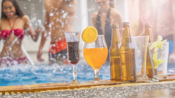 Beverage and juice drink with exotic cocktails and bottle of beer set up on the swimming pool with background of blur people in bikini nude get dance party — Stock Photo, Image