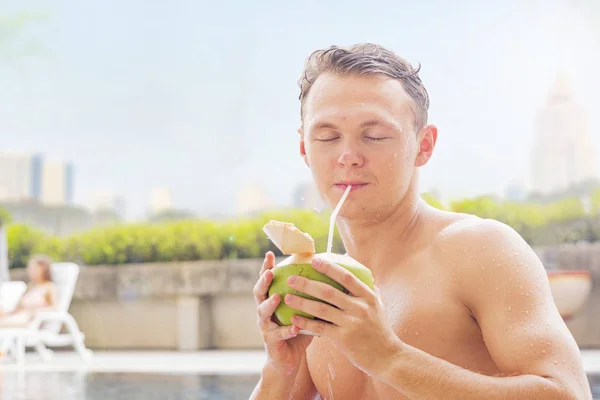 white man muscle nude topless with coconut drink at swimming poo