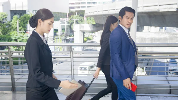 group smart business people of man and woman walk together in rush hour in feeling stress  with tablet smart phone device and luggage at the outdoor pedestrian walkway space in the morning.
