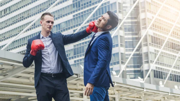 Dos hombres de negocios están luchando con el guante de boxeo en la ciudad al aire libre —  Fotos de Stock