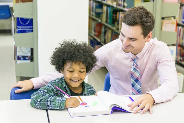 Мужчина учитель и ребенок ученик учиться с книгой на книжной полке фоне — стоковое фото