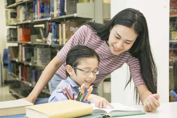 Mujer profesor y niño estudiante aprender con libro en librería fondo — Foto de Stock