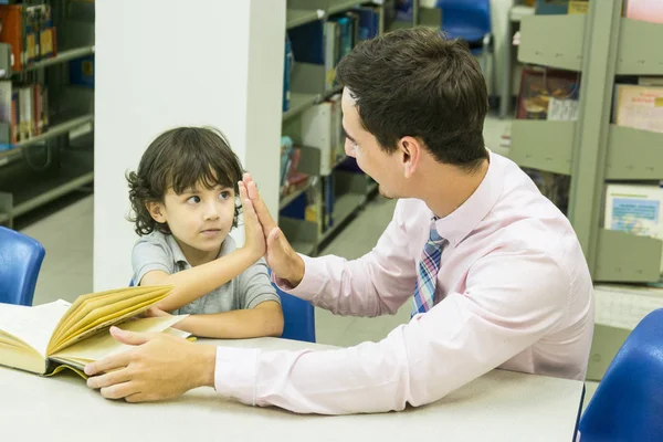 Uomo insegnante e bambino studente imparare con libro a libreria sfondo — Foto Stock