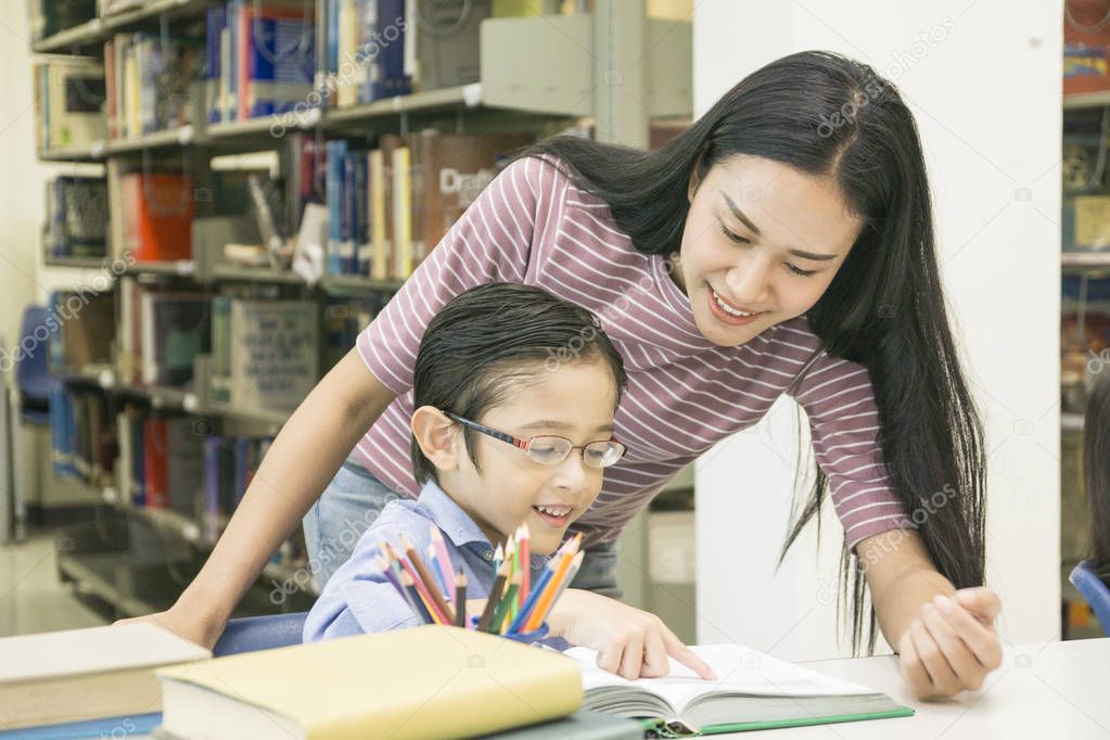 woman teacher and kid student learn with book at bookshelf background