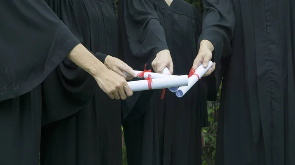 Personnes avec des robes de graduation noires détiennent un diplôme . — Photo