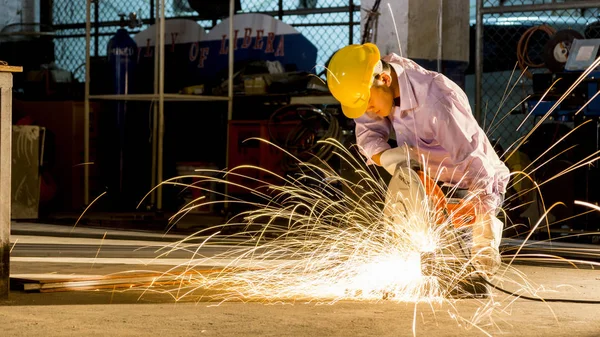 Trabalhador usa moagem corte de metal, foco na linha de luz flash de faísca afiada, em baixa luz — Fotografia de Stock