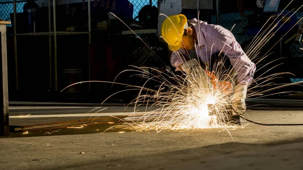 worker uses grinding cut metal, focus on flash light line of sharp spark,in low light